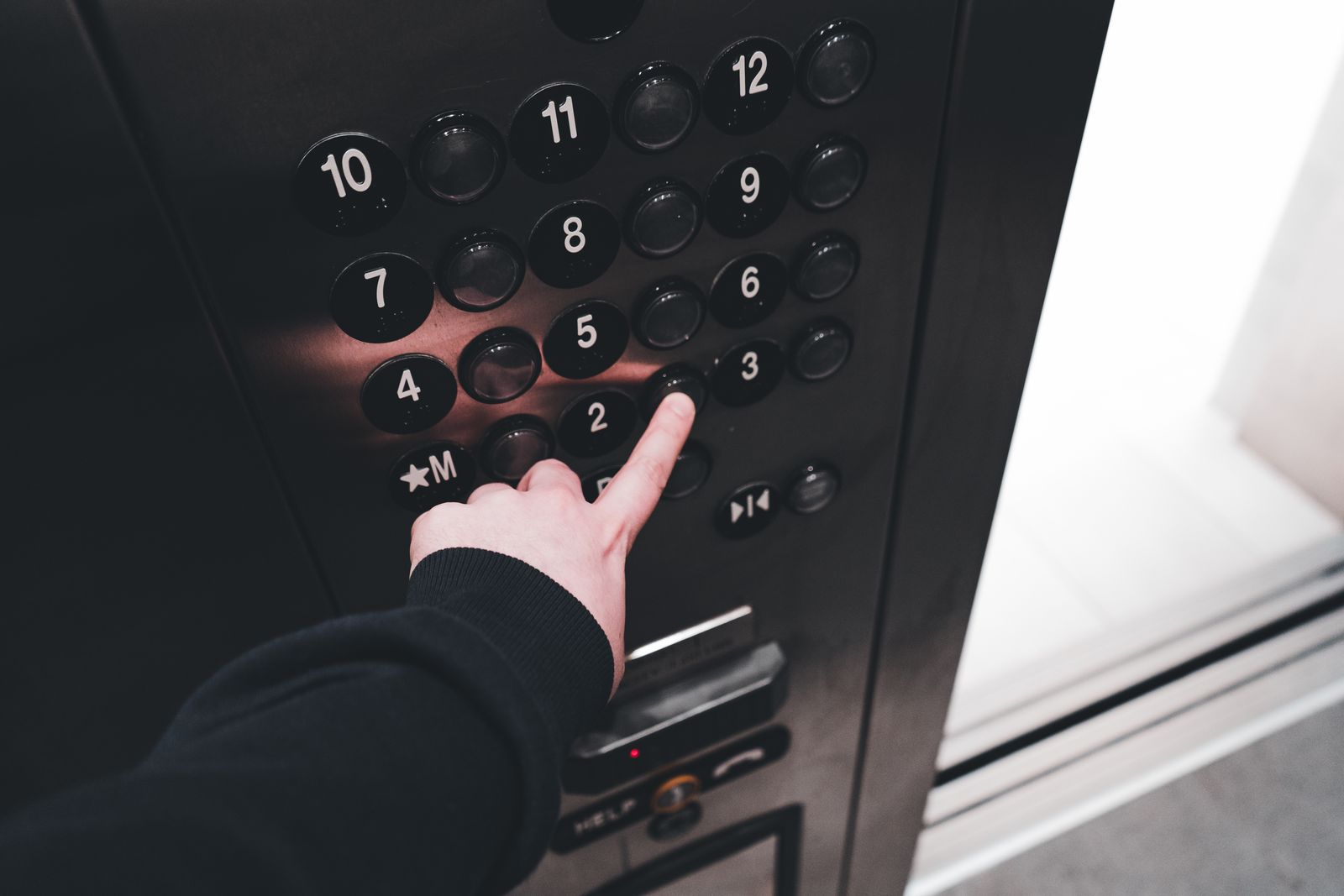 A hand pressing a floor button inside an elevator