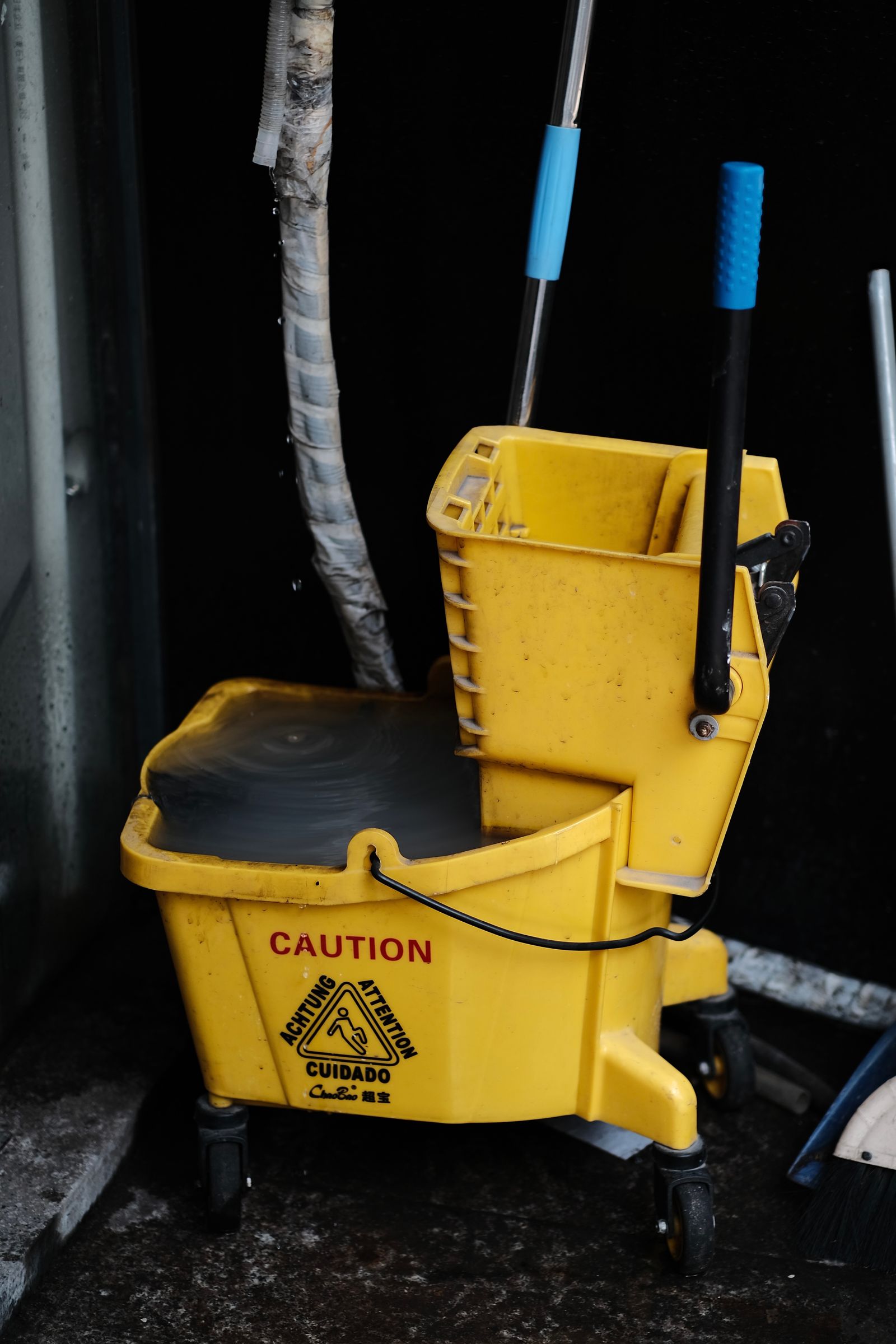 Yellow mop bucket beside a wet-floor caution sign