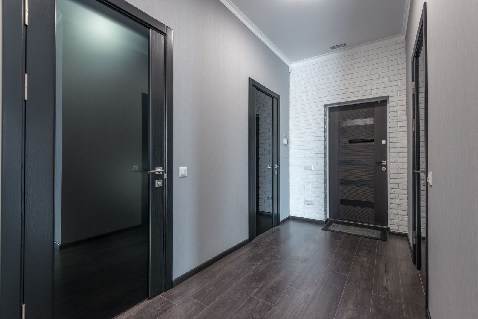 Empty residential corridor with a laminate floor and dark doors